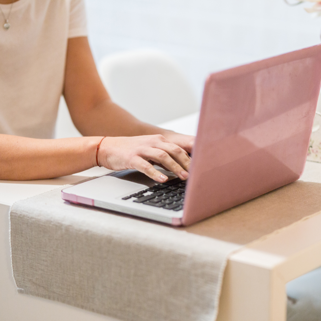 Woman working on pink laptop at her desk