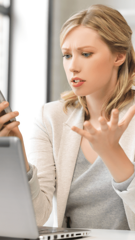 Woman looking at phone with hand up in frustration