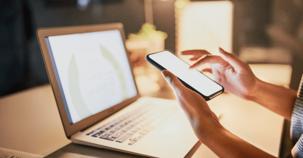 Person on phone and laptop checking LinkedIn